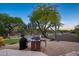 Backyard with a barbecue grill area, green lawn, desert landscaping, and mature trees at 6765 E Duane Ln, Scottsdale, AZ 85266