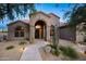 Charming front elevation showcasing arched entry, desert landscaping and walkway lighting at 6765 E Duane Ln, Scottsdale, AZ 85266