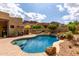 Backyard with a pool and waterfall surrounded by desert landscaping, ideal for relaxation and entertainment at 9938 E Little Nugget Way, Gold Canyon, AZ 85118