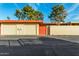 Exterior shot of a garage with two doors and a red pedestrian gate; lush green trees in the background at 10040 W Royal Oak Rd # N, Sun City, AZ 85351
