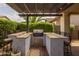 Covered outdoor kitchen with a grill, bar seating, and attractive blue and white patterned tile surround at 10154 E Bergeron Ave, Mesa, AZ 85212