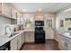 Well-lit kitchen with modern black appliances, white cabinets, granite counters, and wood-look flooring at 1210 W Missouri Ave, Phoenix, AZ 85013