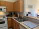 Well lit kitchen featuring wood cabinets, white appliances, and stainless steel sink at 1406 W Emerald Ave # 124, Mesa, AZ 85202