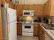 Cozy kitchen with wood cabinetry, white refrigerator, and a white microwave at 1406 W Emerald Ave # 124, Mesa, AZ 85202