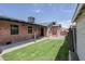 Backyard featuring a grass lawn, concrete, and brick exterior of the home, offering a charming outdoor space at 1551 W Vernon Ave, Phoenix, AZ 85007