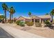 Charming single story home with desert landscaping, lush palms, and a two-car garage at 16280 W Desert Winds Dr, Surprise, AZ 85374