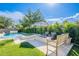 Relax in this backyard retreat with a pool, spa, fire pit, seating, green grass, and lush landscaping at 18868 E Mockingbird Dr, Queen Creek, AZ 85142