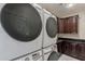 Well-equipped laundry area with stacked washer and dryer, complemented by dark wood cabinets for storage and organization at 18868 E Mockingbird Dr, Queen Creek, AZ 85142