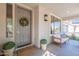 Cozy front porch with a seating area, decorative wreath on the door, and potted plants at 18868 E Mockingbird Dr, Queen Creek, AZ 85142