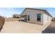 Rear view of home with covered patio, dark-trimmed windows and block wall in the unfinished backyard at 23417 W Burton Ave, Buckeye, AZ 85326