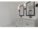 Bright bathroom with double sink vanity, black fixtures and hardware, and decorative wall sconces at 23417 W Burton Ave, Buckeye, AZ 85326