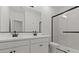 Modern bathroom featuring a dual sink vanity, large mirror, and a glass-enclosed shower with black trim at 23417 W Burton Ave, Buckeye, AZ 85326