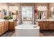 Bathroom featuring large soaking tub, separate vanities with wood cabinetry, and mirrors at 26853 N 89Th Dr, Peoria, AZ 85383