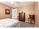 Bright bedroom with a comfortable bed, wooden dresser, and ceiling fan, leading to a carpeted hall at 26853 N 89Th Dr, Peoria, AZ 85383