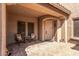 Inviting covered patio with brick paving, seating for two, and a view of the front entrance and windows at 26853 N 89Th Dr, Peoria, AZ 85383