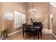 Dining room with a chandelier hanging over a wooden table and two windows with white shutters at 26853 N 89Th Dr, Peoria, AZ 85383