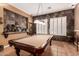 Game room featuring a pool table, stone accent wall, and bright windows with shutter blinds at 26853 N 89Th Dr, Peoria, AZ 85383