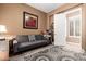 Comfortable living room with a couch, rug, and art, adjacent to a tiled room and a sunny open door at 26853 N 89Th Dr, Peoria, AZ 85383
