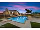 Expansive backyard featuring a sparkling pool, lounge area, lush grass, and an outdoor kitchen at 5044 W Electra Ln, Glendale, AZ 85310