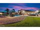 Expansive backyard featuring a pool, multiple seating areas, lush landscaping, and a covered patio with a TV at 5044 W Electra Ln, Glendale, AZ 85310