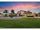 Lush backyard with a sparkling pool, lounge chairs, outdoor kitchen, covered patio, and green grass at 5044 W Electra Ln, Glendale, AZ 85310