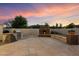 Outdoor kitchen with a stone grill and a custom fireplace in a backyard with beautiful stone paving at 5044 W Electra Ln, Glendale, AZ 85310