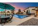 Beautiful backyard pool with a blue umbrella, outdoor seating, a lush lawn, and a charming home exterior at 5044 W Electra Ln, Glendale, AZ 85310
