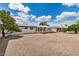 Single story home with a white exterior, an awning, a gravel yard, and mature landscaping under a bright blue, partly cloudy sky at 5818 E Colby St, Mesa, AZ 85205