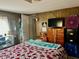 Bedroom features a floral bedspread, wood-paneled walls, and television at 5933 E Main St # 114, Mesa, AZ 85206