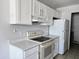 This kitchen features white cabinets, a white refrigerator and a white range/oven at 6901 W Mackenzie Dr # 1287, Phoenix, AZ 85033