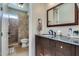 Bathroom featuring a dark vanity, a decorative mirror, and a tiled walk-in shower for a luxurious experience at 8830 S 20Th S Pl, Phoenix, AZ 85042