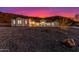 Dramatic front exterior of desert home at twilight, with soft lighting enhancing its architectural features and desert surroundings at 9357 W Canyon Verde Dr, Casa Grande, AZ 85194