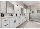 Modern bathroom featuring dual sinks, white cabinets, sleek mirrors, and a large glass-enclosed shower at 9825 E Gary St, Mesa, AZ 85207