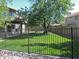 Lush backyard with green lawn, mature shade trees, covered patio, and secure wrought iron fencing at 1010 N Osprey Ct, Gilbert, AZ 85234