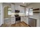 Modern kitchen with stainless steel appliances, white cabinetry, and views of the adjacent living area at 1010 N Osprey Ct, Gilbert, AZ 85234