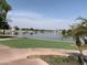 Scenic lake view from the green lawn with palm trees, sidewalk, and some homes in the distance at 1010 N Osprey Ct, Gilbert, AZ 85234
