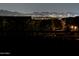 Nighttime view of city lights below dark mountain range, seen from behind a fence and trees at 10623 E Acacia Dr, Scottsdale, AZ 85255