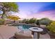 Inviting backyard pool area with lounge chairs, shade umbrella, natural rock waterfall feature, and fire pit at 10623 E Acacia Dr, Scottsdale, AZ 85255