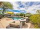 Backyard oasis featuring a sparkling pool, a lush garden, a comfortable seating, and an umbrella at 10623 E Acacia Dr, Scottsdale, AZ 85255