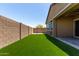 View of the backyard with well-maintained artificial grass, brick perimeter wall, and partial view of the house at 10949 N 183Rd Dr, Surprise, AZ 85388
