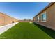 Backyard with artificial grass, a brick wall, and partial view of the house with windows at 10949 N 183Rd Dr, Surprise, AZ 85388