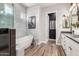 Bright bathroom boasts tiled walls, freestanding tub, walk-in shower, and wood-look tile flooring at 10949 N 183Rd Dr, Surprise, AZ 85388