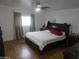 This bedroom features wood floors, neutral walls, a ceiling fan, and large windows at 11770 W Aster Dr, El Mirage, AZ 85335