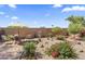 Landscaped backyard featuring a patio set, gravel, shrubs, and a decorative gate sign in a sunny environment at 1241 E Elm Rd, San Tan Valley, AZ 85140