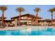 Resort-style community pool with clear blue water, palm trees, and modern building in the background at 1272 W Camina Buena Vis, Queen Creek, AZ 85140