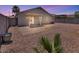 Backyard with covered patio, gravel landscaping, and block wall at dusk at 15802 W Watson Ln, Surprise, AZ 85379
