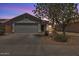 Front view showcasing a two-car garage and desert landscaping at dusk at 15802 W Watson Ln, Surprise, AZ 85379