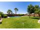 Expansive backyard with lush green grass, palm trees, and a refreshing swimming pool at 18658 N Tanners Way, Maricopa, AZ 85138