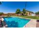 Inviting backyard featuring a sparkling pool, lush lawn, mature trees, and charming string lights at 18658 N Tanners Way, Maricopa, AZ 85138