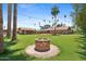 Backyard with a brick fire pit, string lights, lush green grass, and mature trees in the background at 20 W Pasadena Ave, Phoenix, AZ 85013
